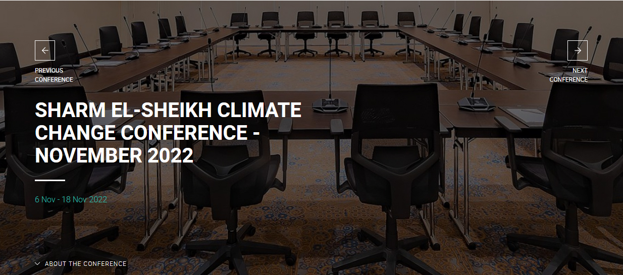 screen shot of cop27 web page of just a big empty conference room table and chairs.