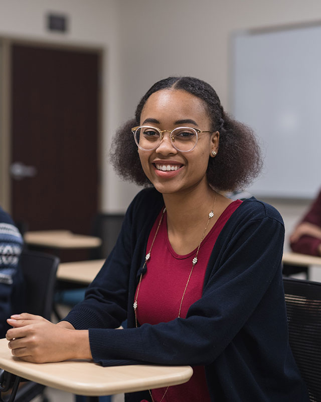 Female student of color smiling in a classroom setting