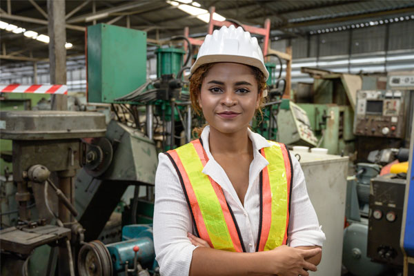 Woman smiling with hard hat in factory setting